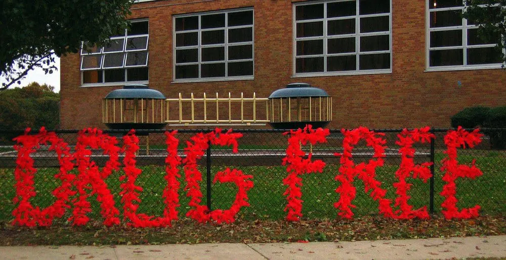 Moving beyond scare tactics and misinformation to understanding addiction illustrated by a drug free sign on a school fence