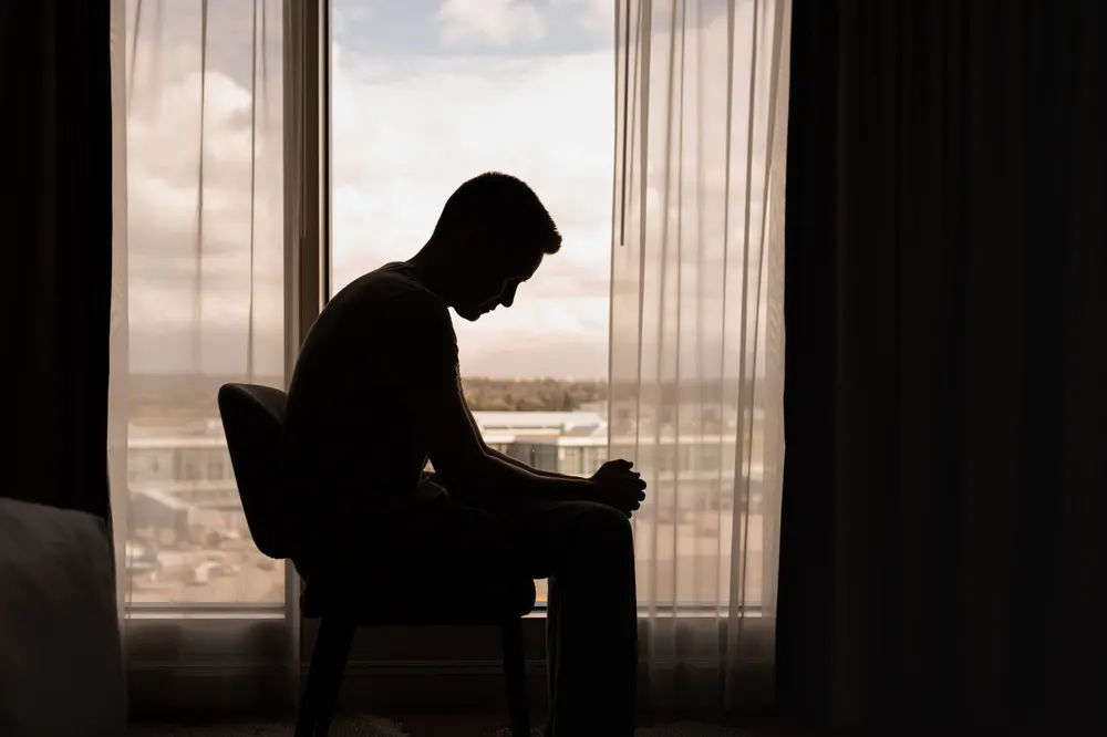 loneliness-man-sitting-in-a-window-alone-drug-or-alcohol-addiction-sober-friends-long-term-sobriety-risk-of-relapsing-normal-part-of-recovery